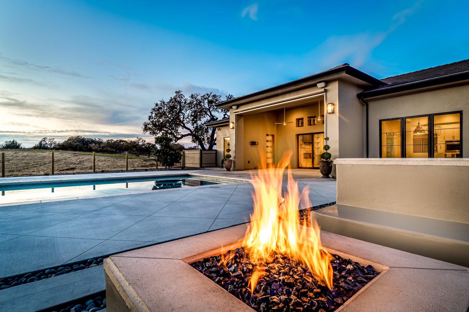 Gas fire feature on concrete decking beside the pool, with oak-covered hills beyond, Templeton