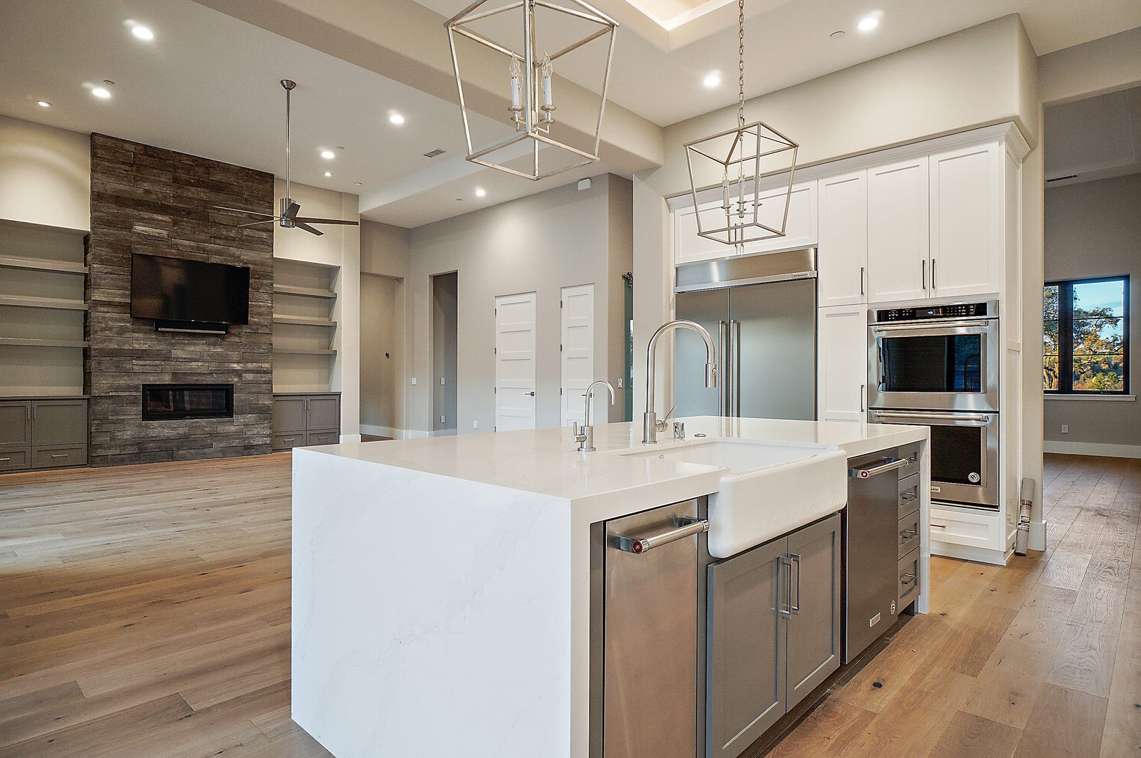 Kitchen with a white waterfall-edge island, farmhouse sink and open view to the great room fireplace, Templeton