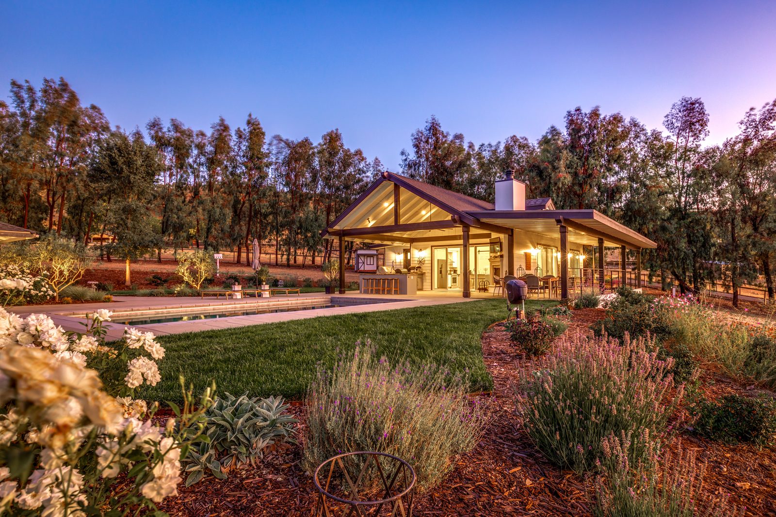 Detached guest house with a gabled covered porch at dusk, framed by lavender and oaks, Paso Robles