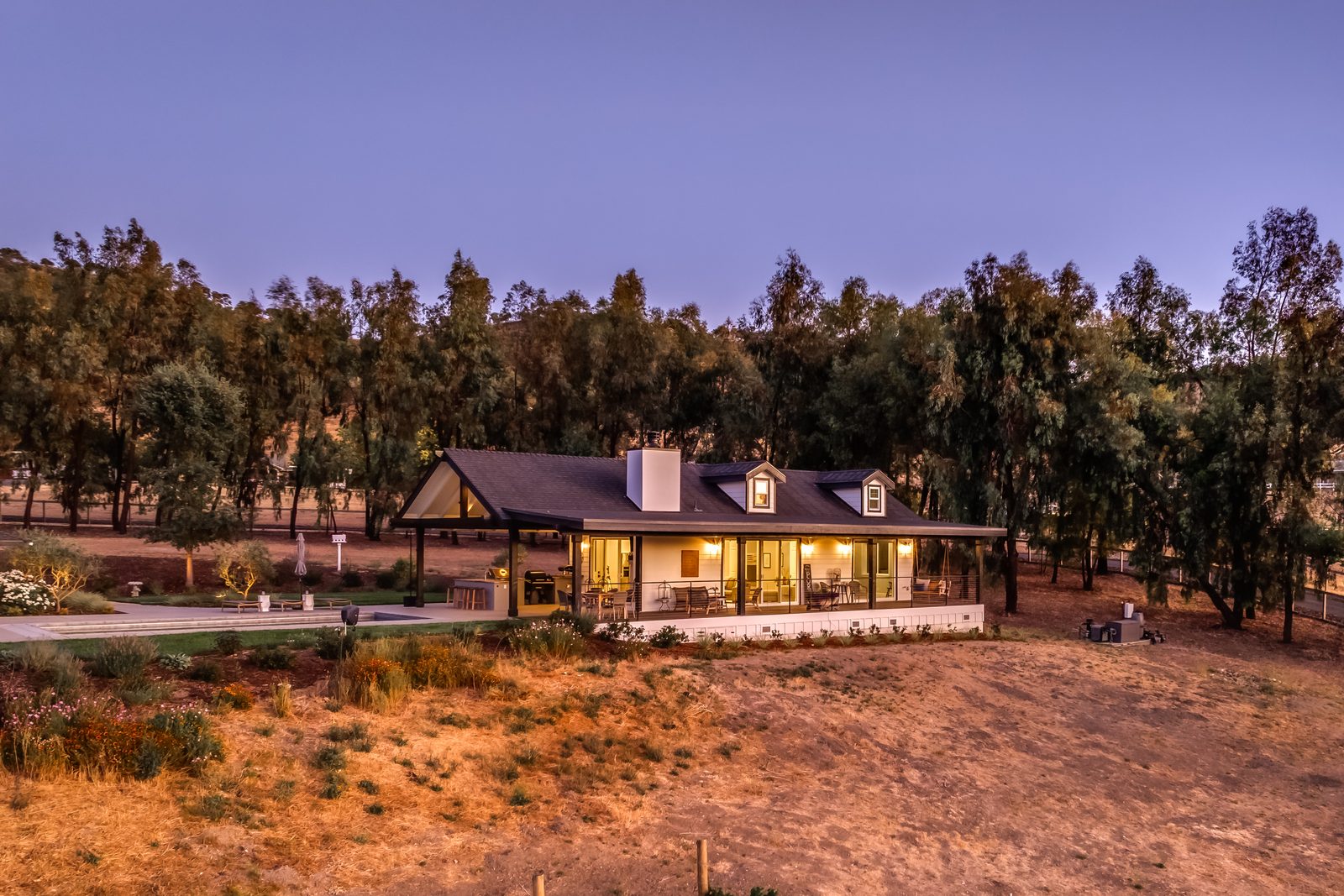 Guest house with dormers and a wraparound covered porch at dusk, Paso Robles