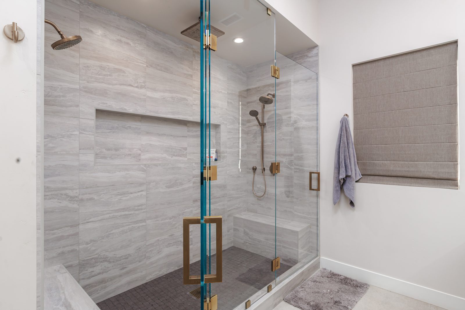 Walk-in shower with frameless glass, large-format gray tile and brass fixtures, Templeton