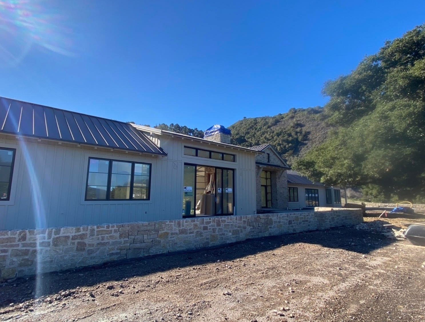 Custom home under construction with board-and-batten siding, a metal roof and a new stone wall, Santa Lucia Preserve, Carmel