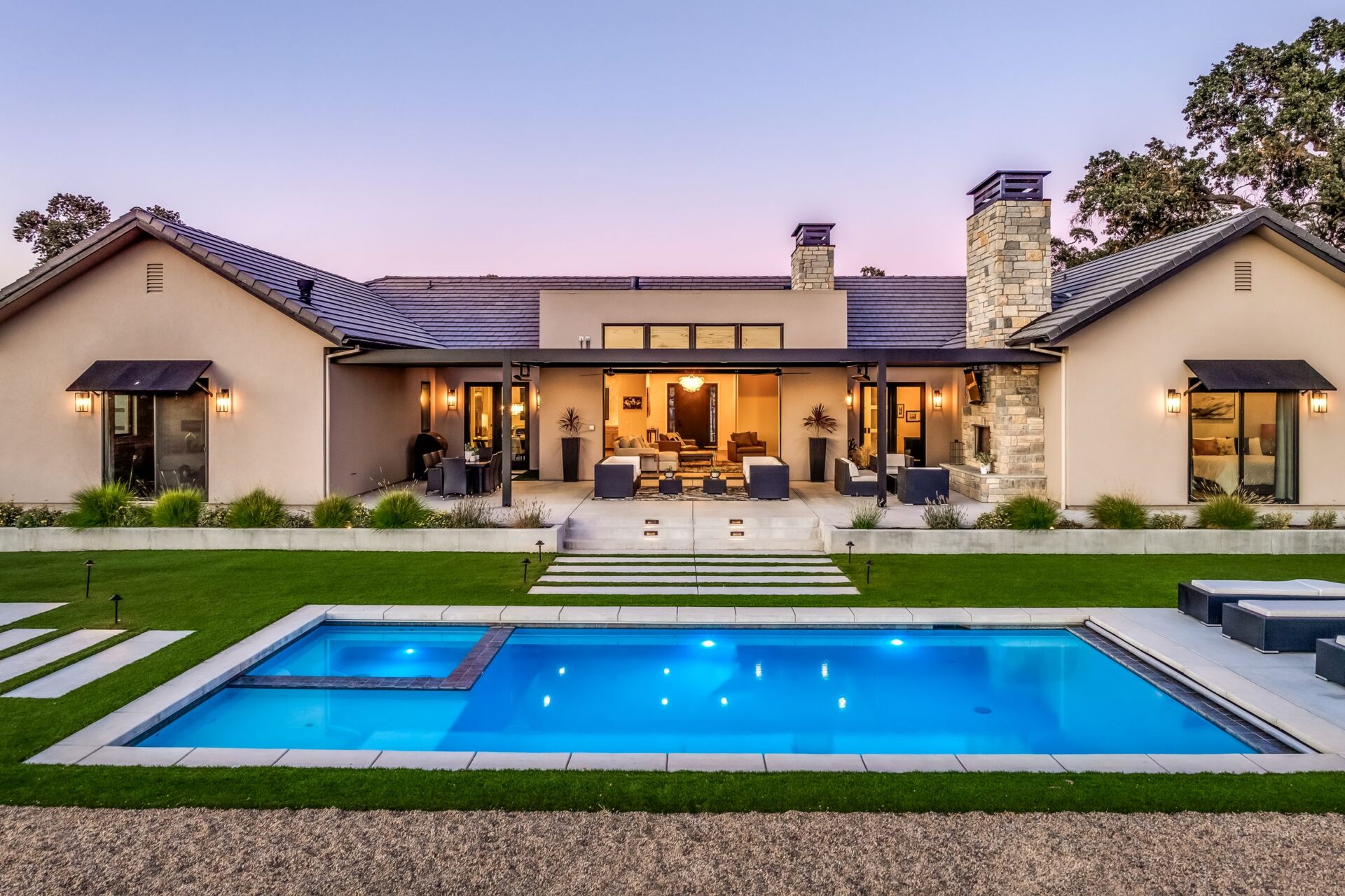 Modern Ranch custom home at dusk with lit pool and covered patio, Templeton